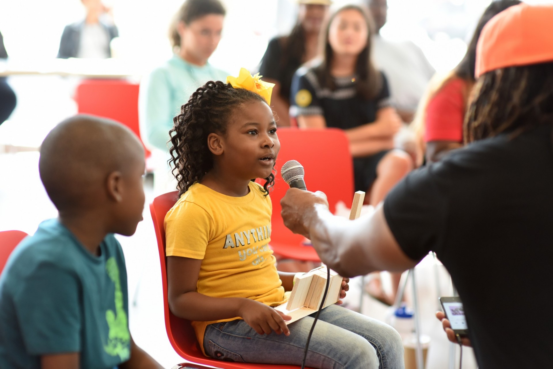 Instructor holds a microphone up to a young child in the audience during Community Day at The Forum