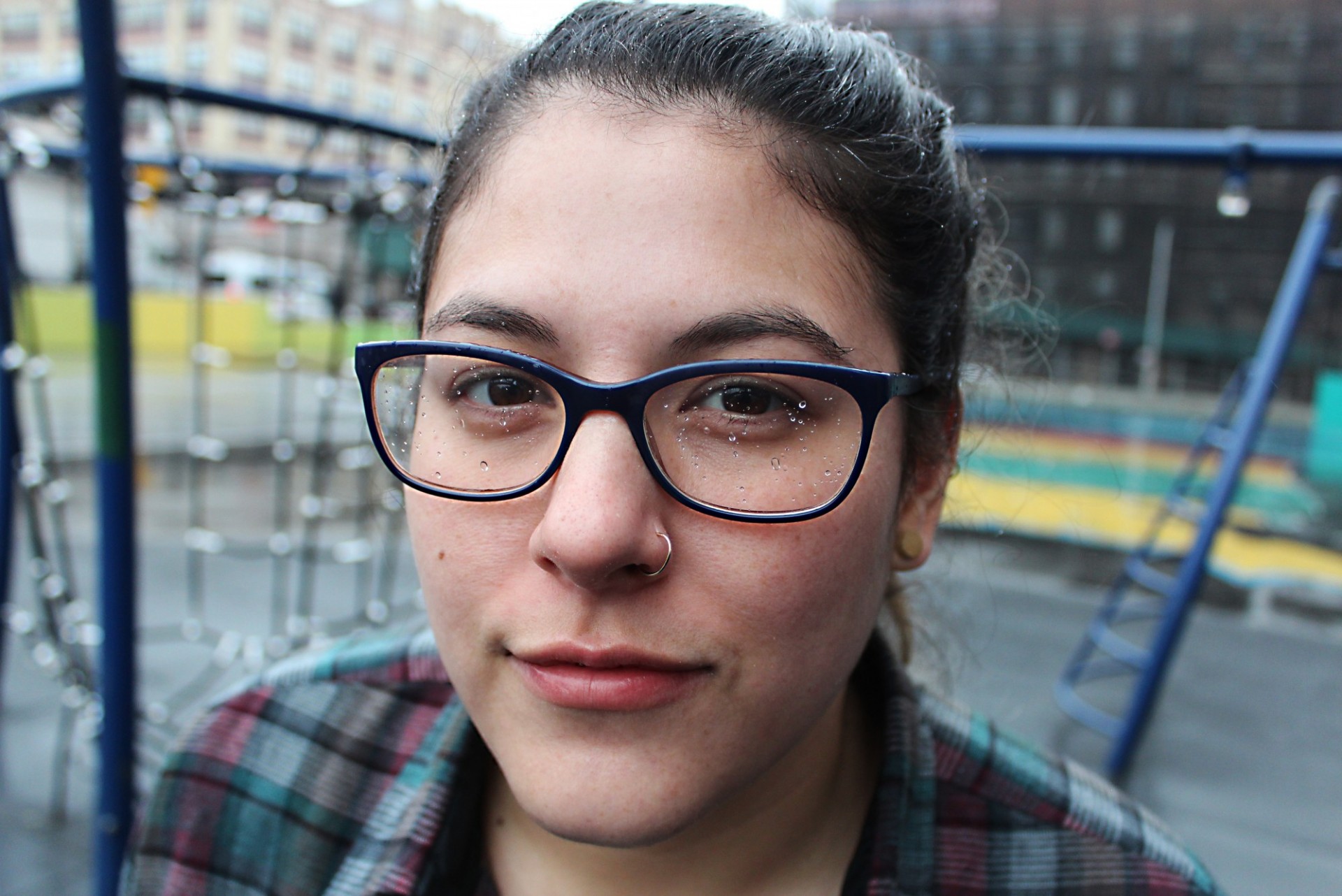 Close up of young woman with glasses looking at camera with playground in background