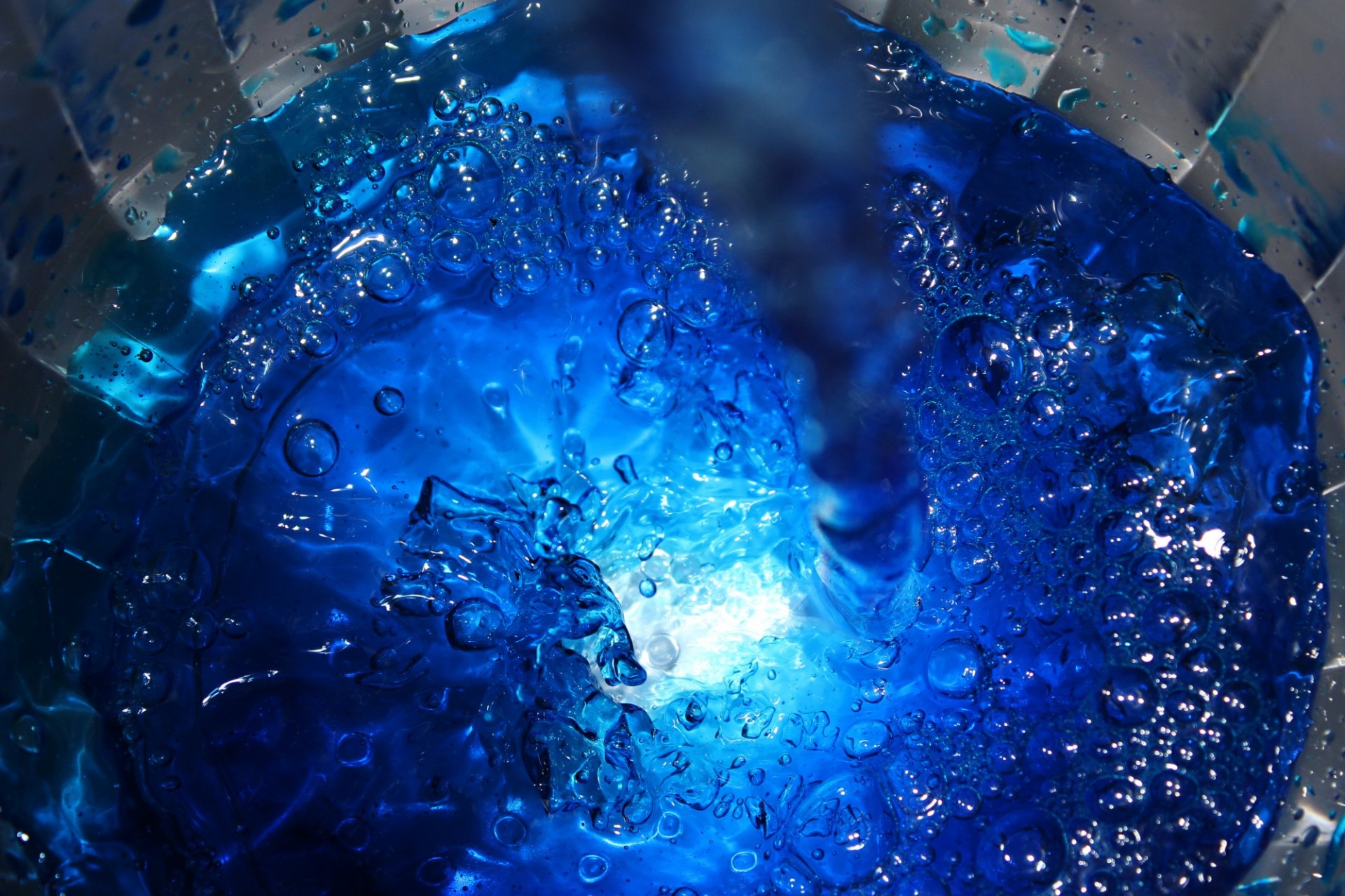 Image of blue water with bubbles and a light source penetrating the center of the water