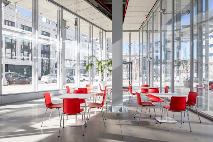 Multiple cafe tables with four red chairs at each spread out across the Forum's glass walled Atrium