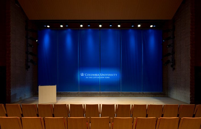Front view of the Auditorium stage with no setup and screen is up