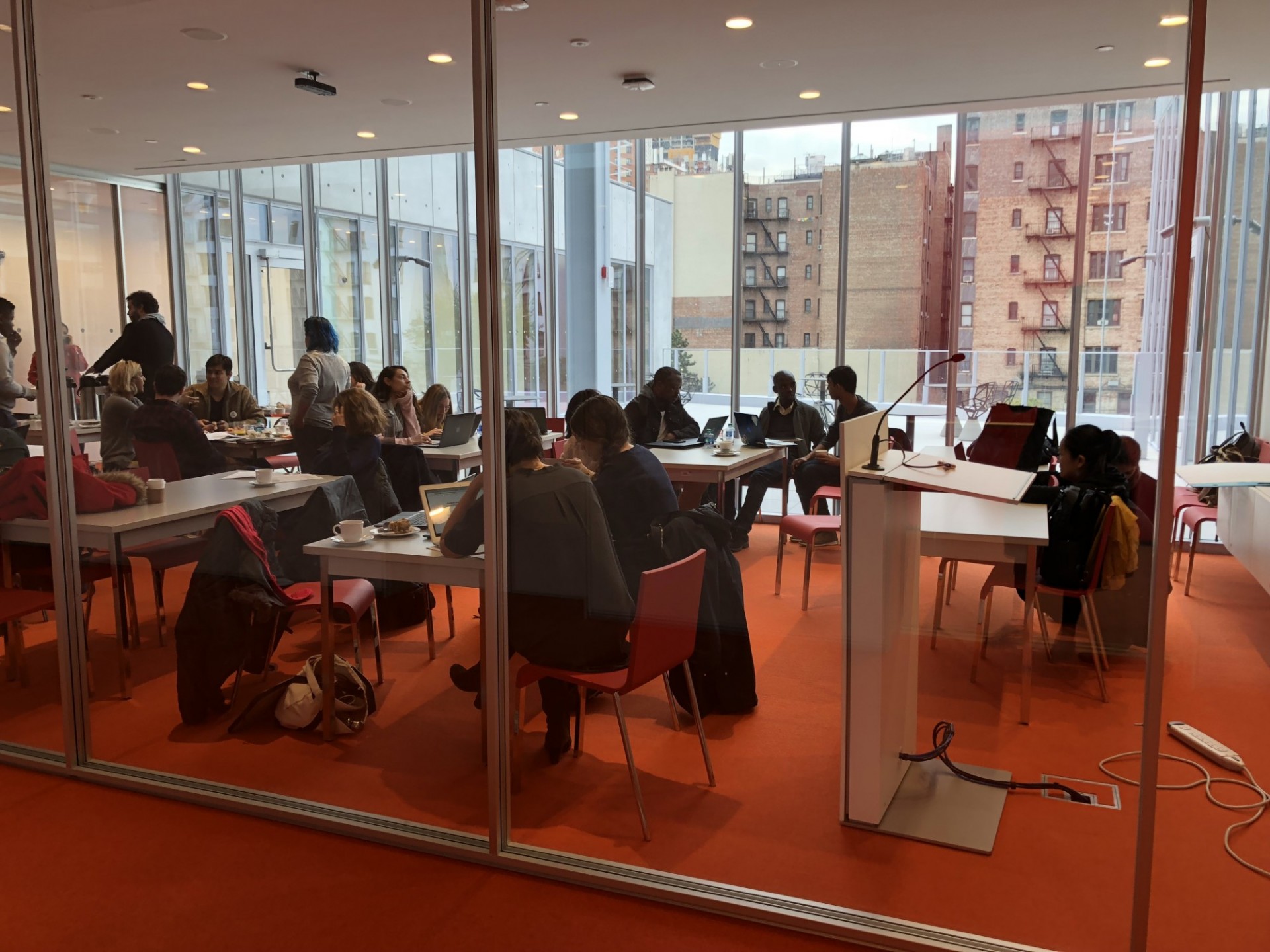Event in The Forum's room 301. Groups of people sit in pairs, working around tables. 