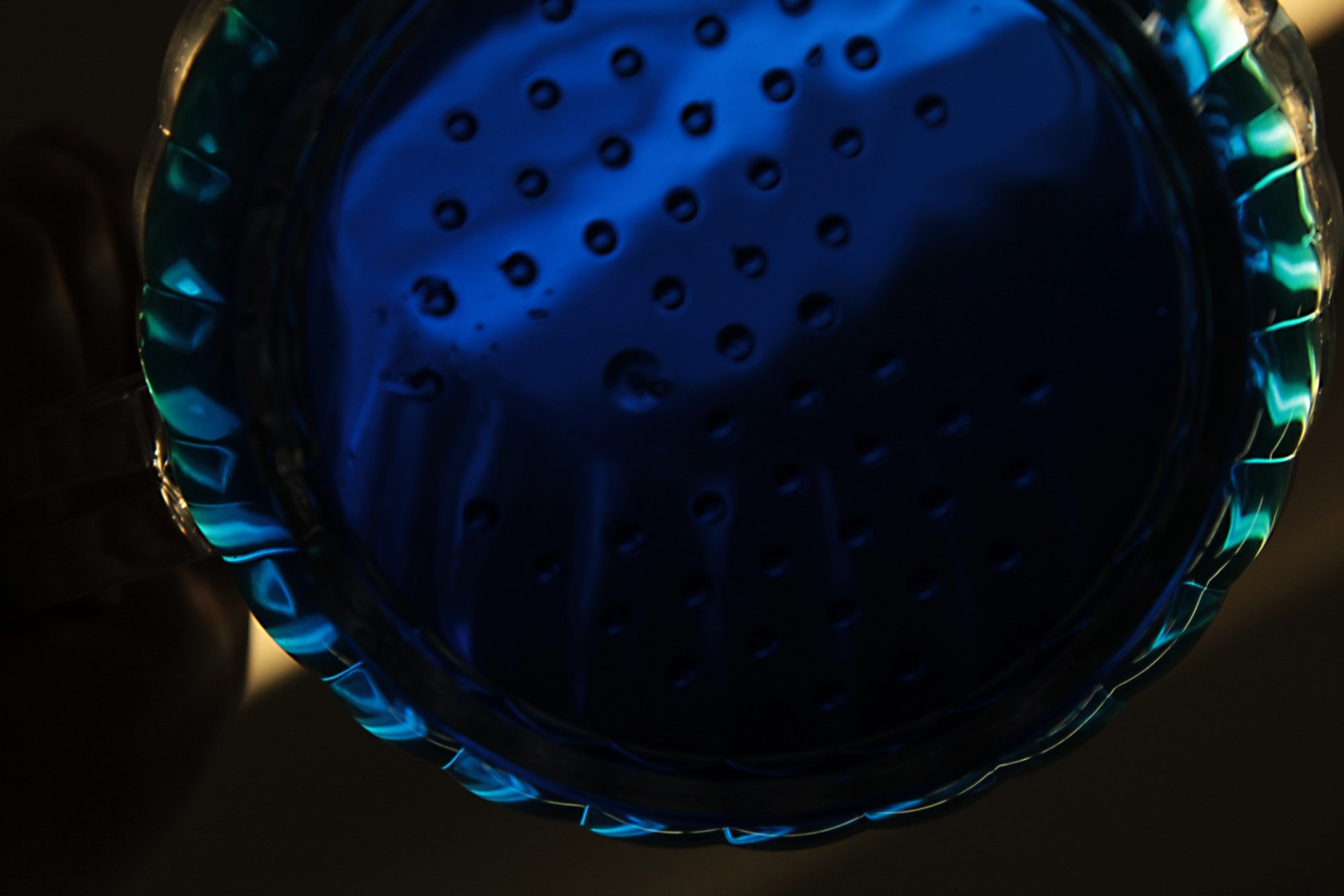 Close-up, dark image of a hard-to-distinguish round object, perhaps a shower head