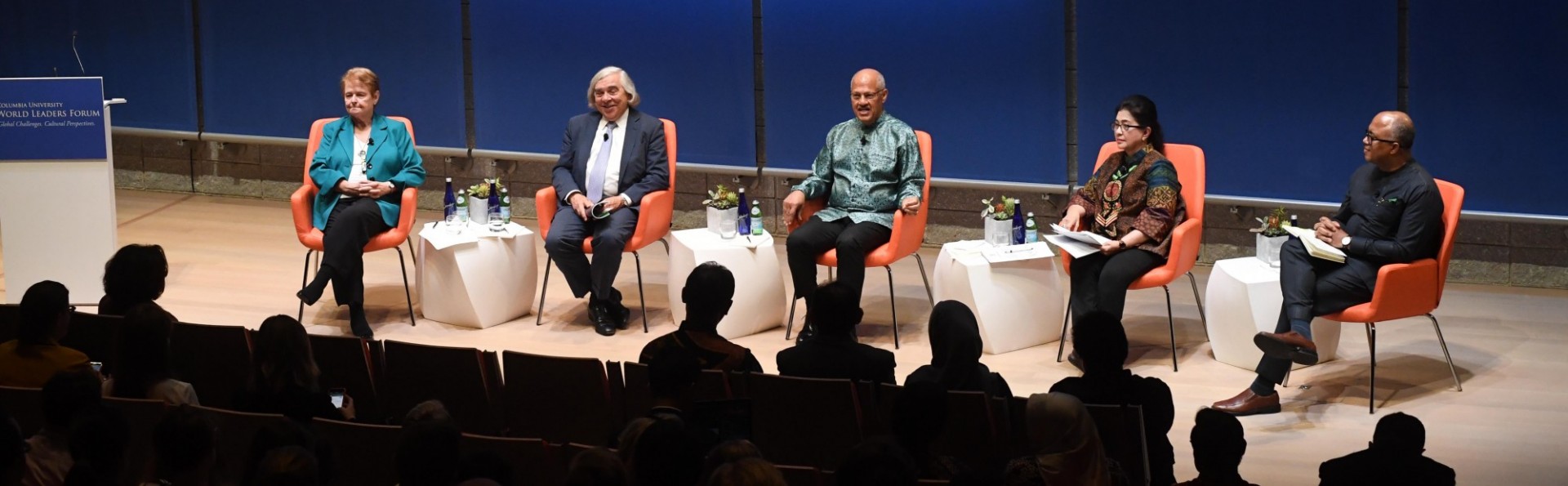 Panel event in the Forum auditorium with five people seated in a row of chairs across the stage