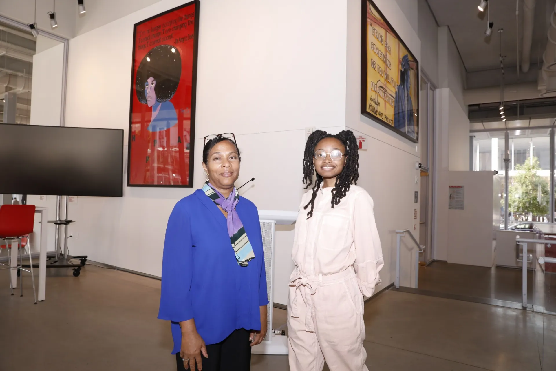 Two artists pose by paintings