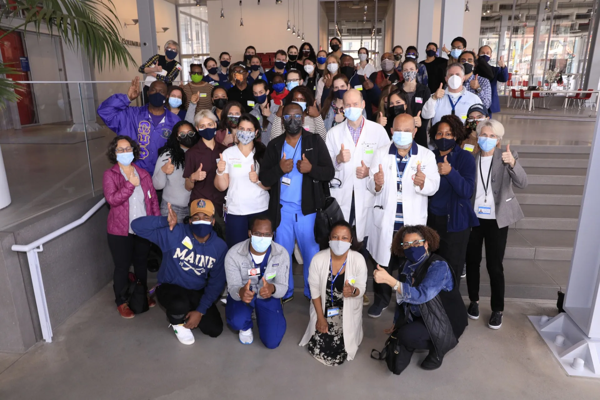 Group of volunteers poses together inside on the stairs of The Forum's Atrium