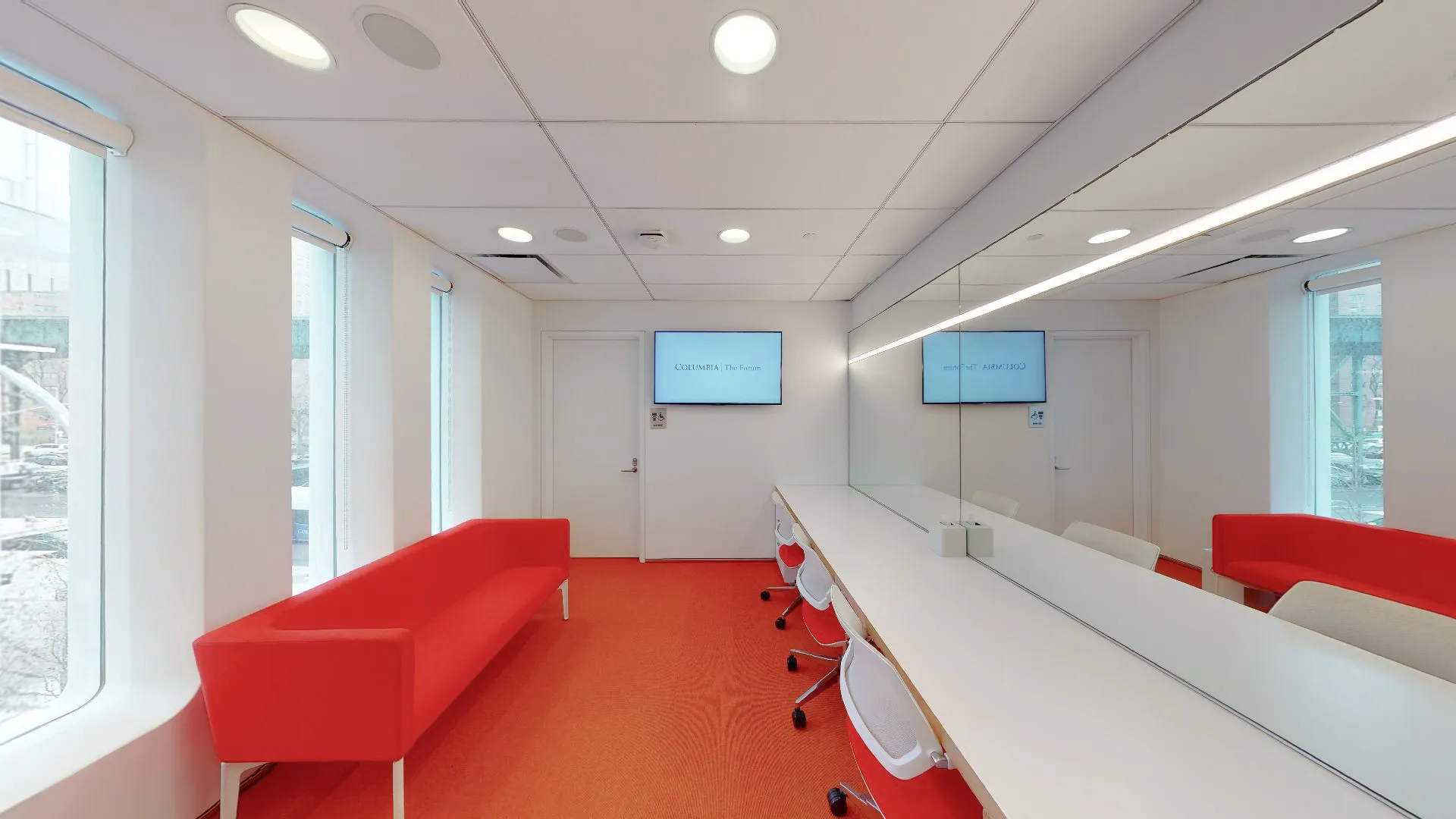 The Forum green room featuring a red sofa across from a mirrored vanity with three chairs