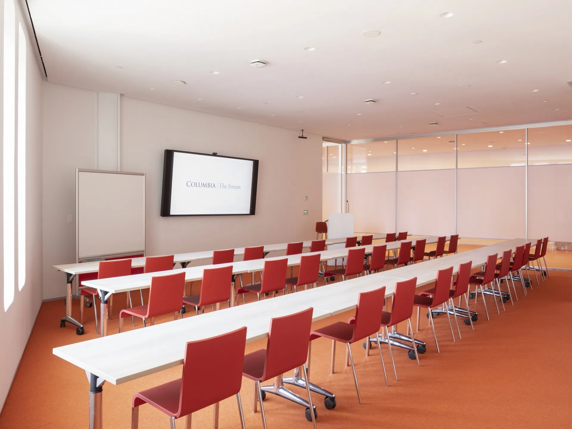 The Forum room 315 with tables and chairs arranged classroom-style facing the front of the room and podium